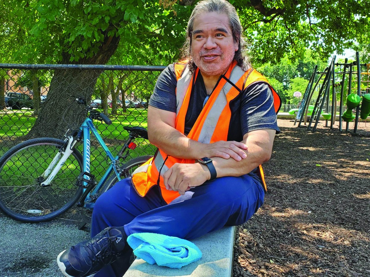Youth soccer coach Ernie Alvarez sits on a bench in Douglass Park