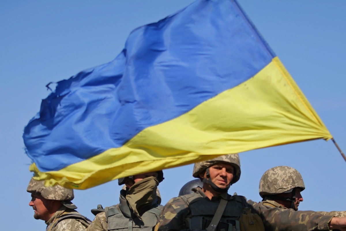 Ukrainian soldiers with a blue and yellow Ukraine flag flying overhead
