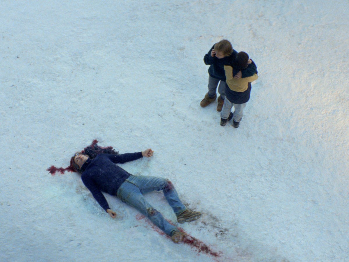 two people call for help next to a bleeding body in the snow