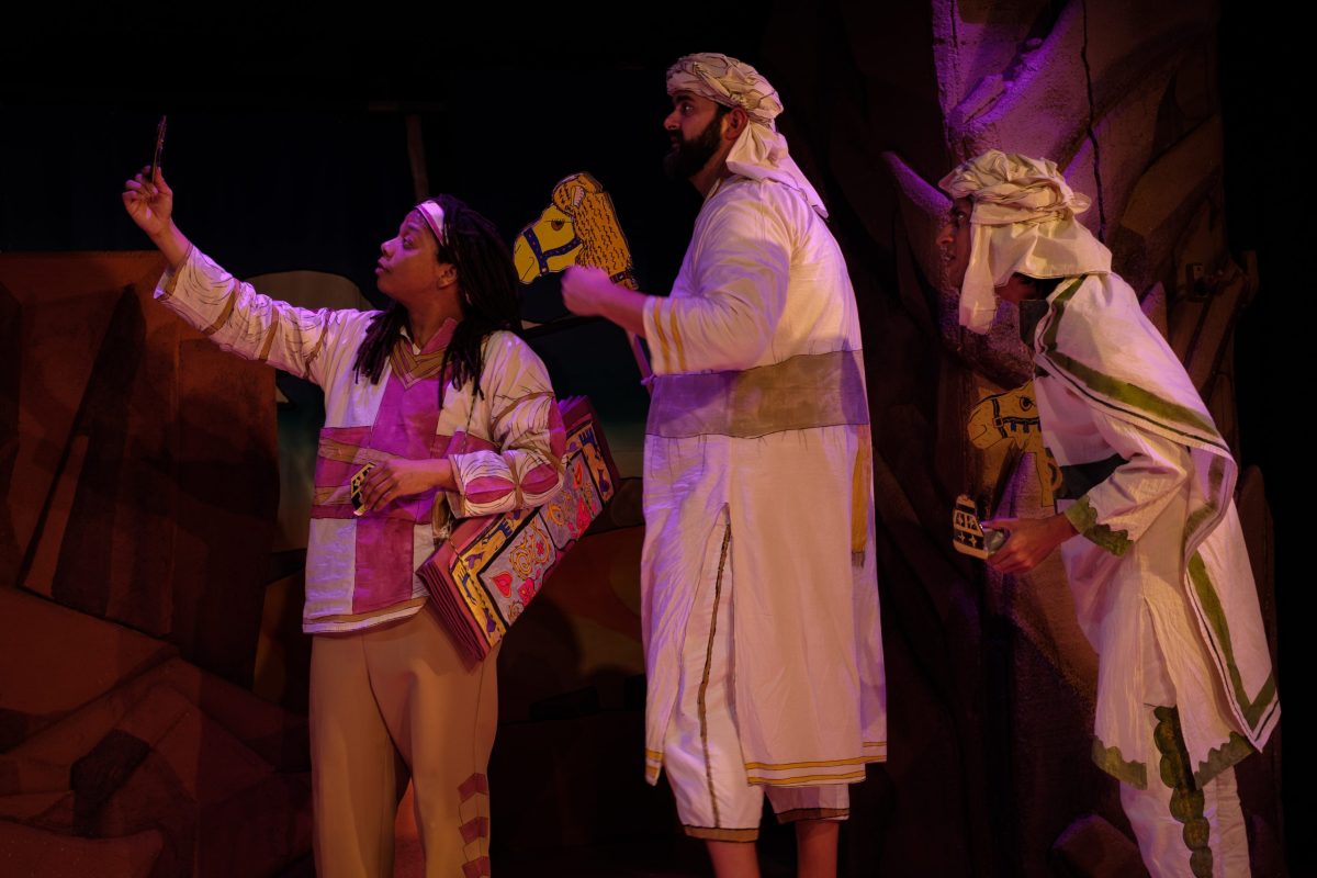 The Three Wise Men are shown in profile, holding stick camels and looking at an astrolabe held up by the man at left.