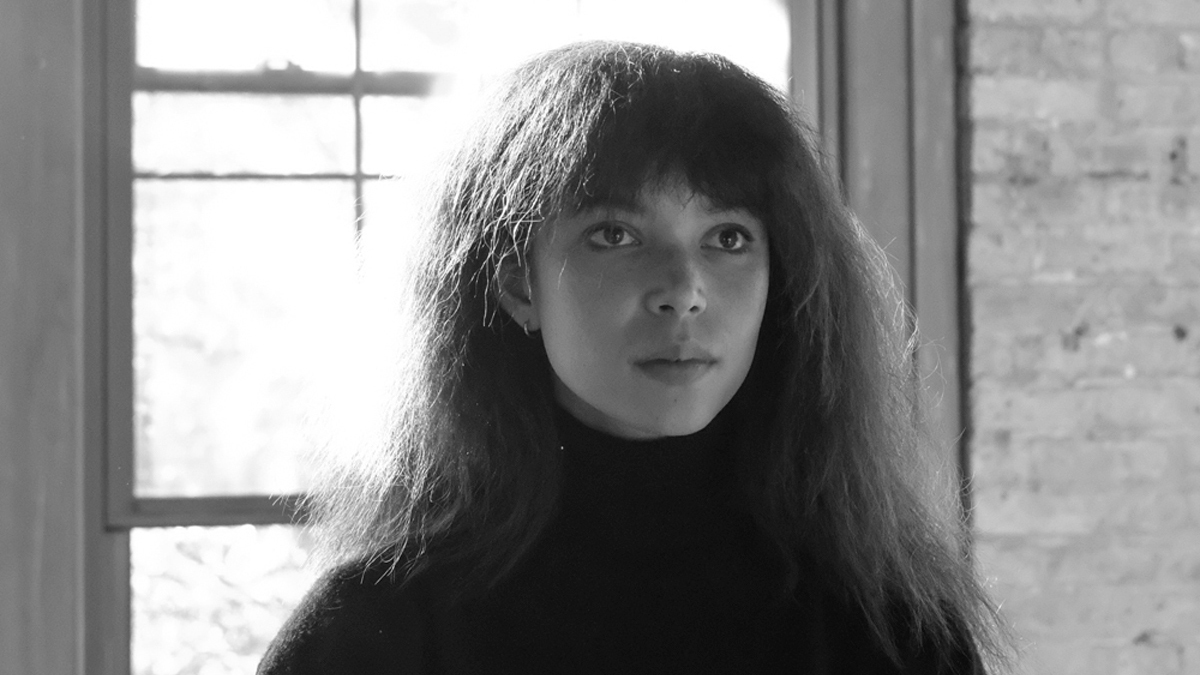 Dorothy Carlos in black and white, posing serenely indoors in front of a bright window and looking slightly to the left of the camera