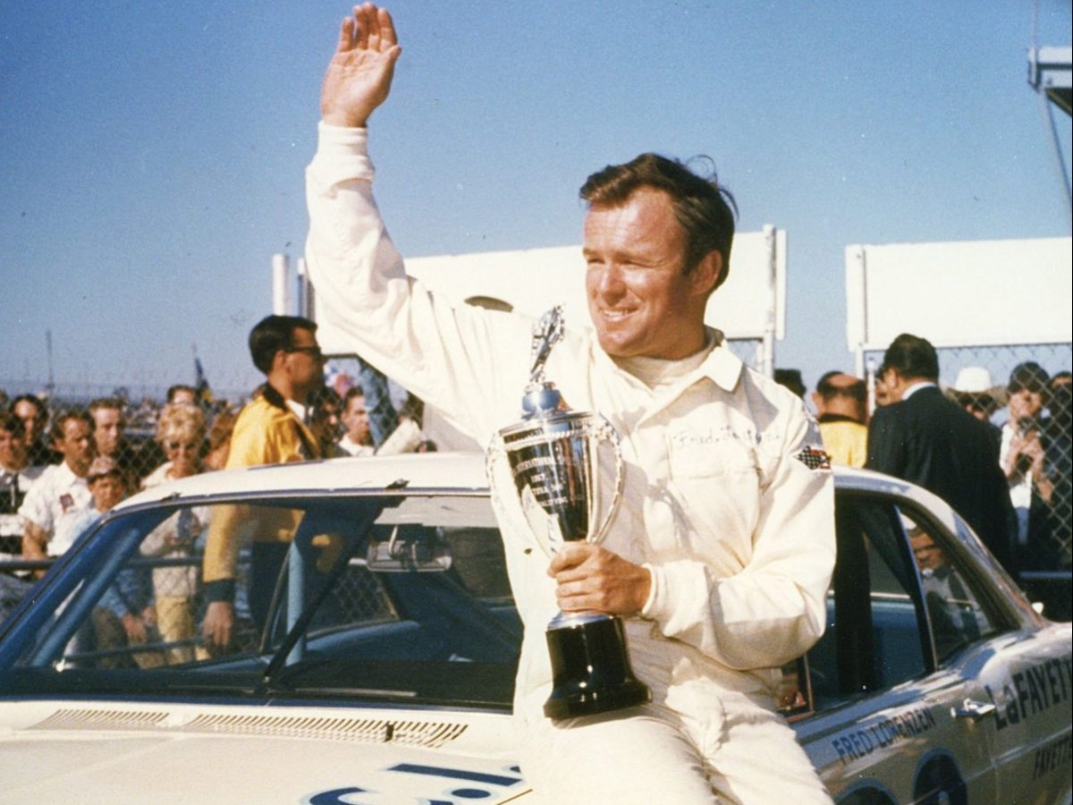 1967 photo of fred lorenzen sitting on top of his white stock racing car holding a trophy