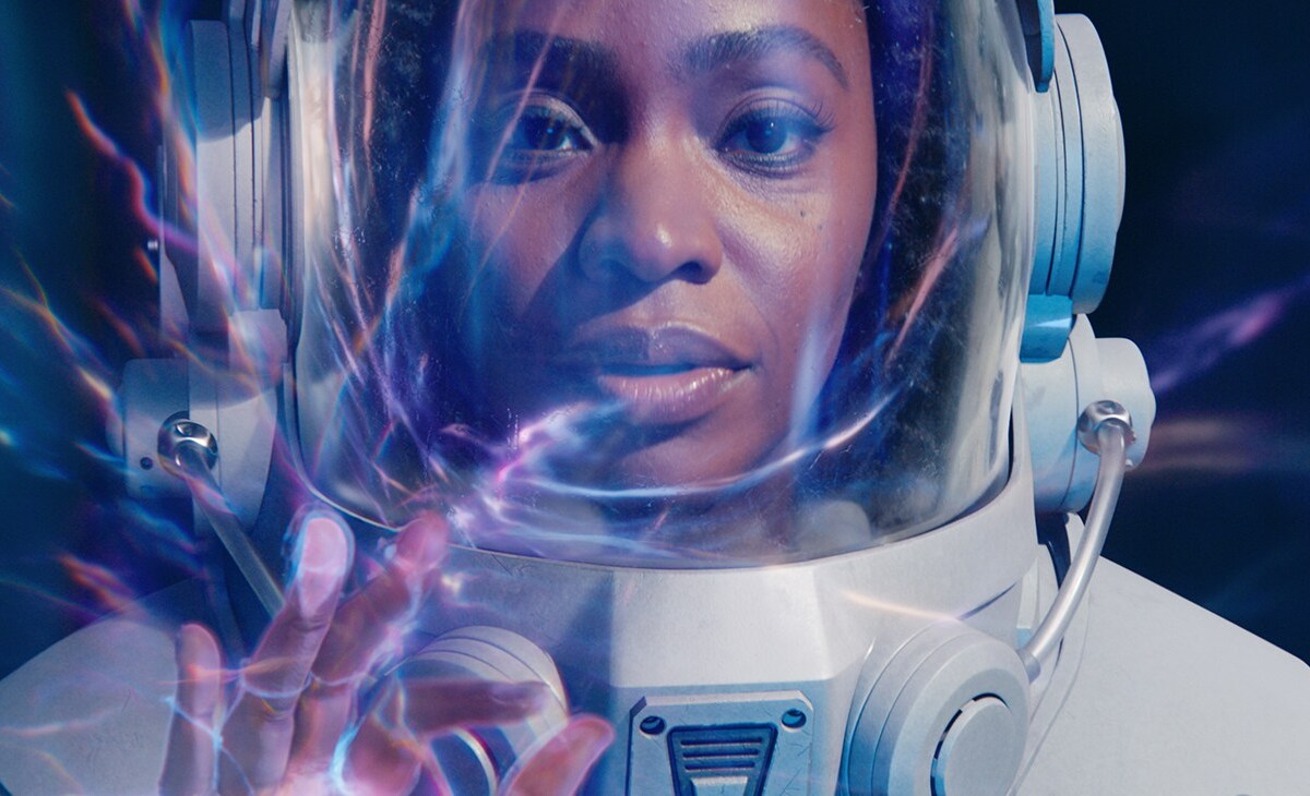 a Black woman in a space suit reaches out her fingers