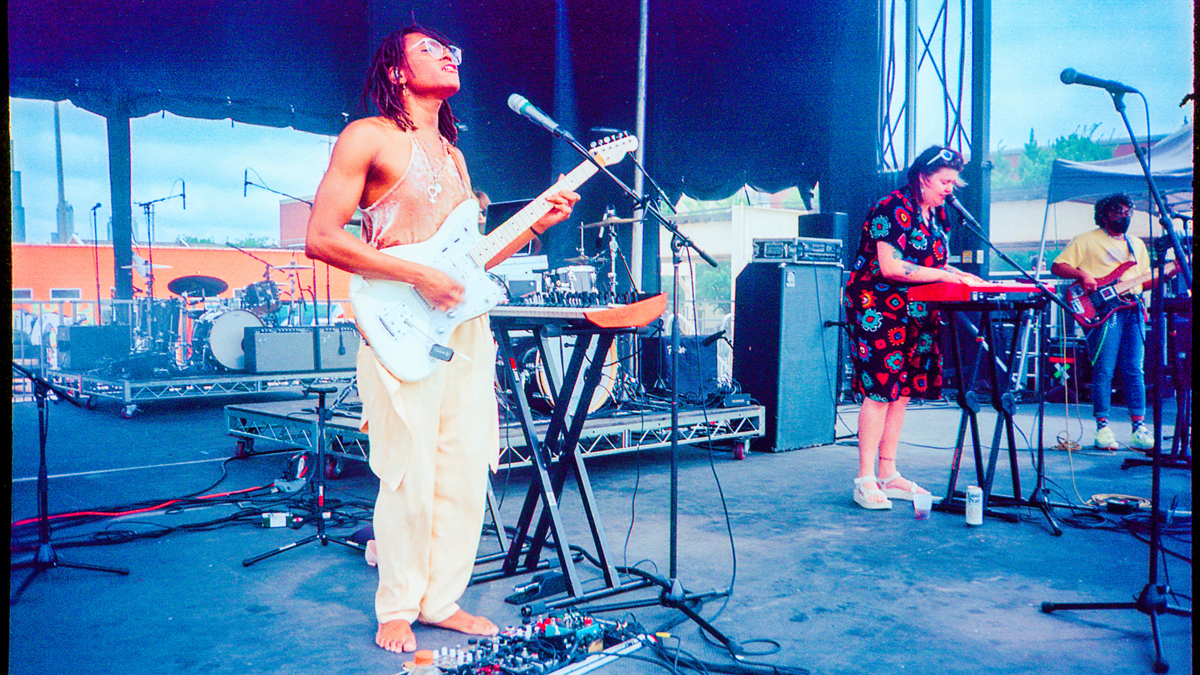 Manae Solara Vaughn and two visible bandmates on a large outdoor festival stage