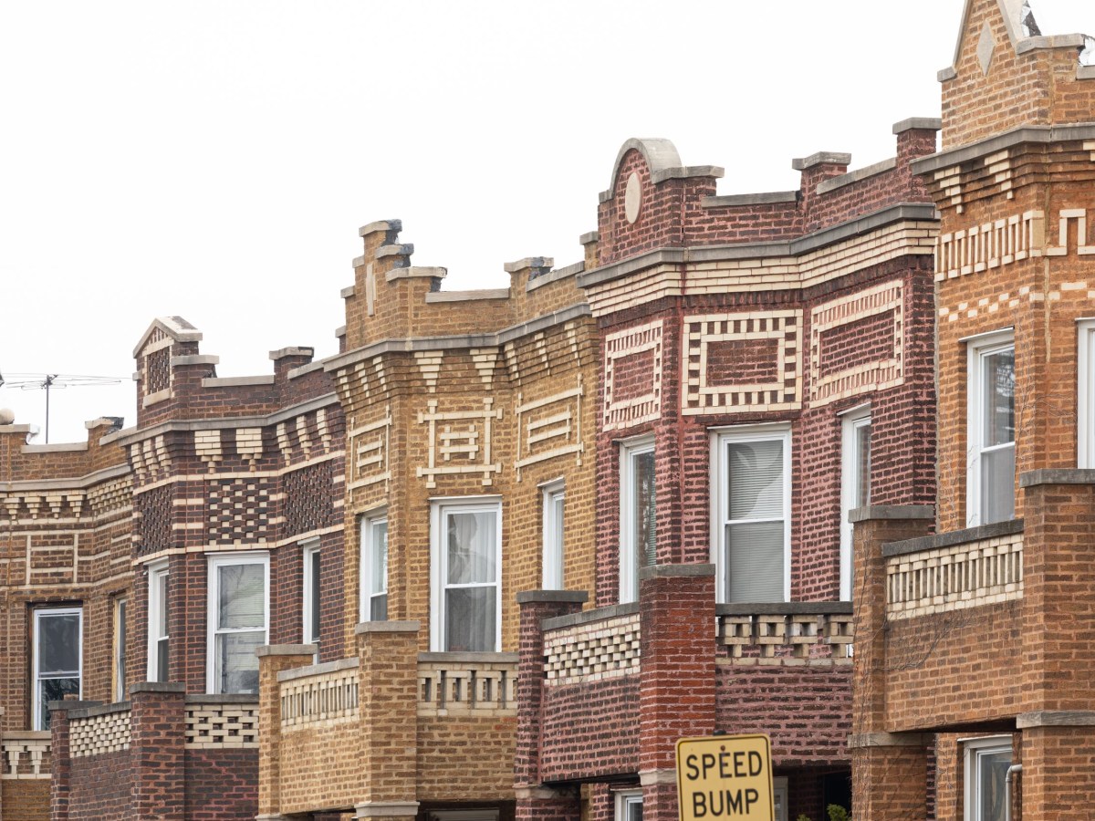 Photo shows the tops of a series of attached brick buildings with detailed, multicolored brick cornices