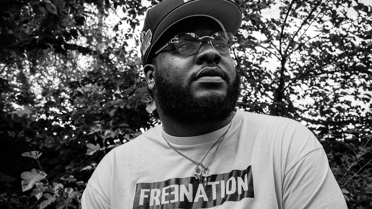 Stock Marley wears a Free Nation T-shirt in an outdoor black-and-white photo with a backdrop of tree branches