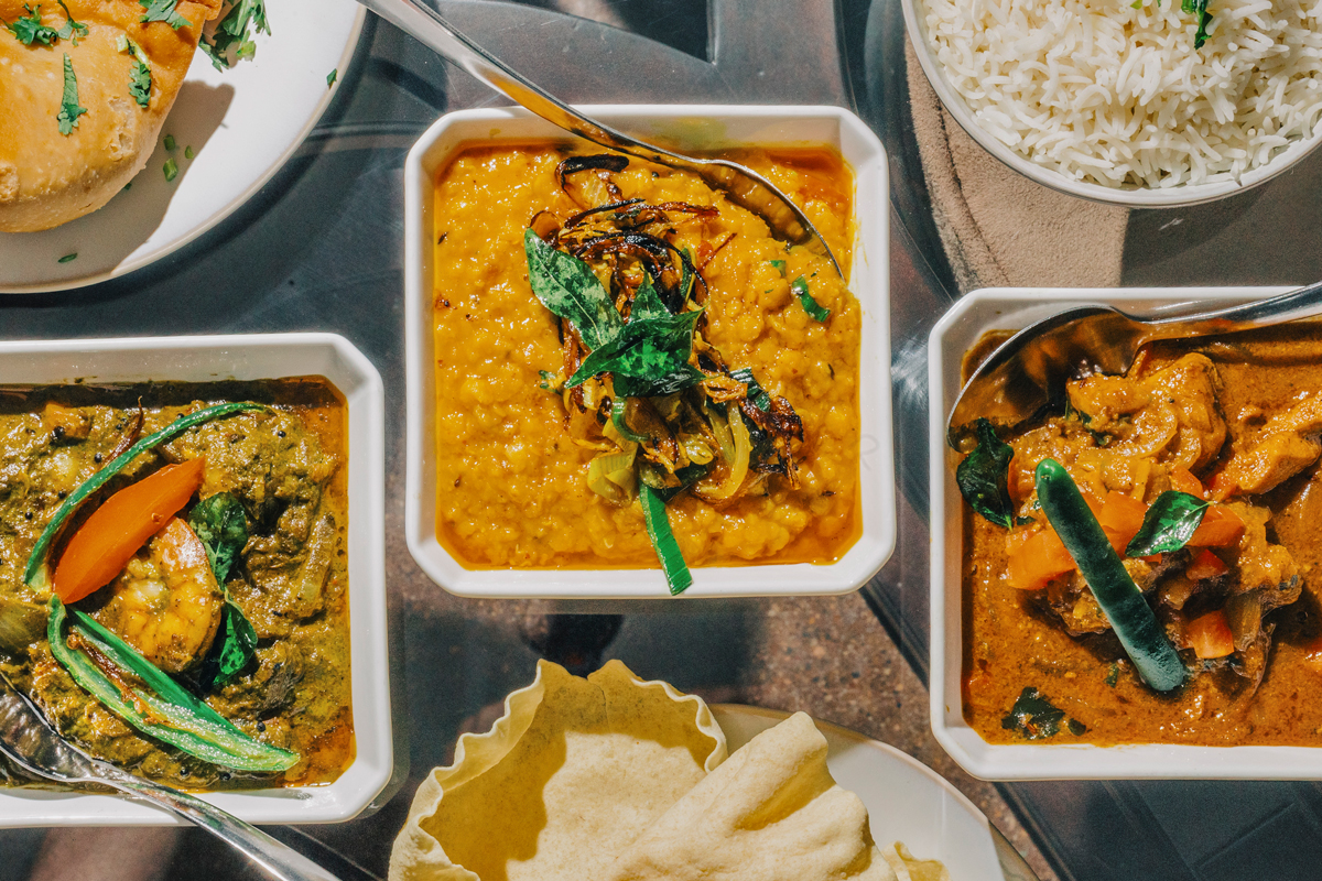 brightly colored Sri Lankan food lined up in white square bowls
