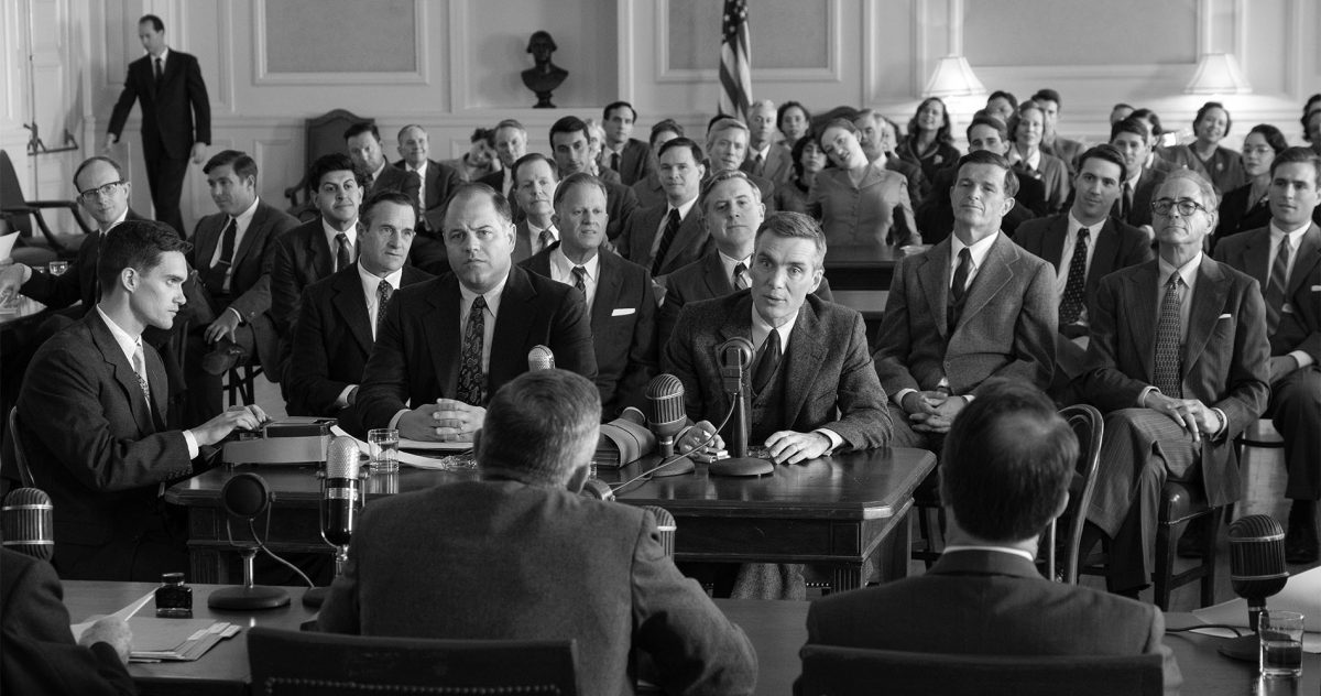 A black-and-white photo from the film Oppenheimer, depicting a hearing.