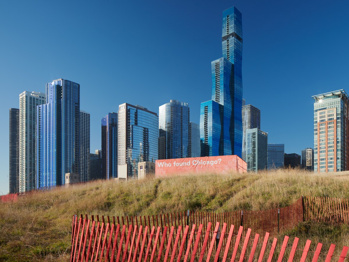 In the background stands Chicago's skyline, in the foreground is a patch of prairie with a red sign that reads: Who found Chicago? and a red fence.