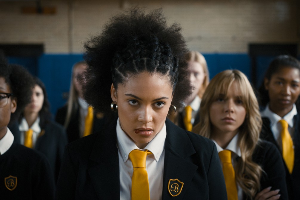 a Black teen in a school uniform stares ahead