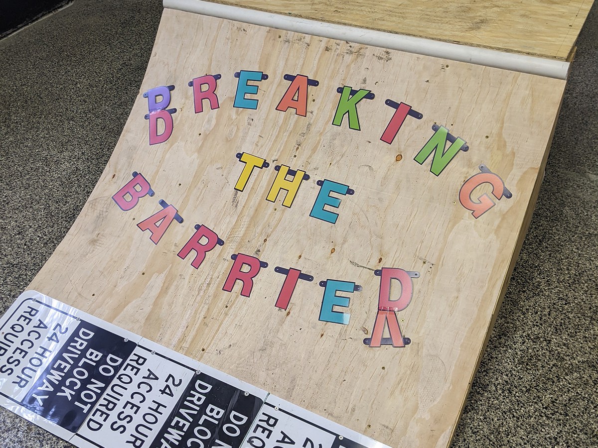 A wooden skate ramp decorated with colorful block letters that read "Breaking the Barrier."