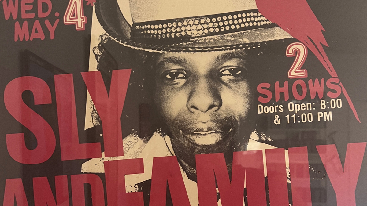 A poster or flyer for the show where One Eyed Jacks backed Sly Stone at the Red Parrot in New York City on May 4, 1983, showing Stone in a tall brimmed hat with a spangled band and large red letting superimposed over him
