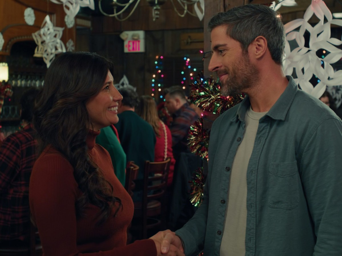 a white man and woman shake hands in a room decorated for Christmas
