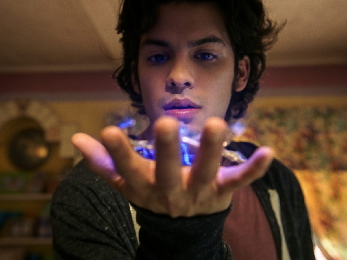 a young man holds a glowing alien beetle in his open hand