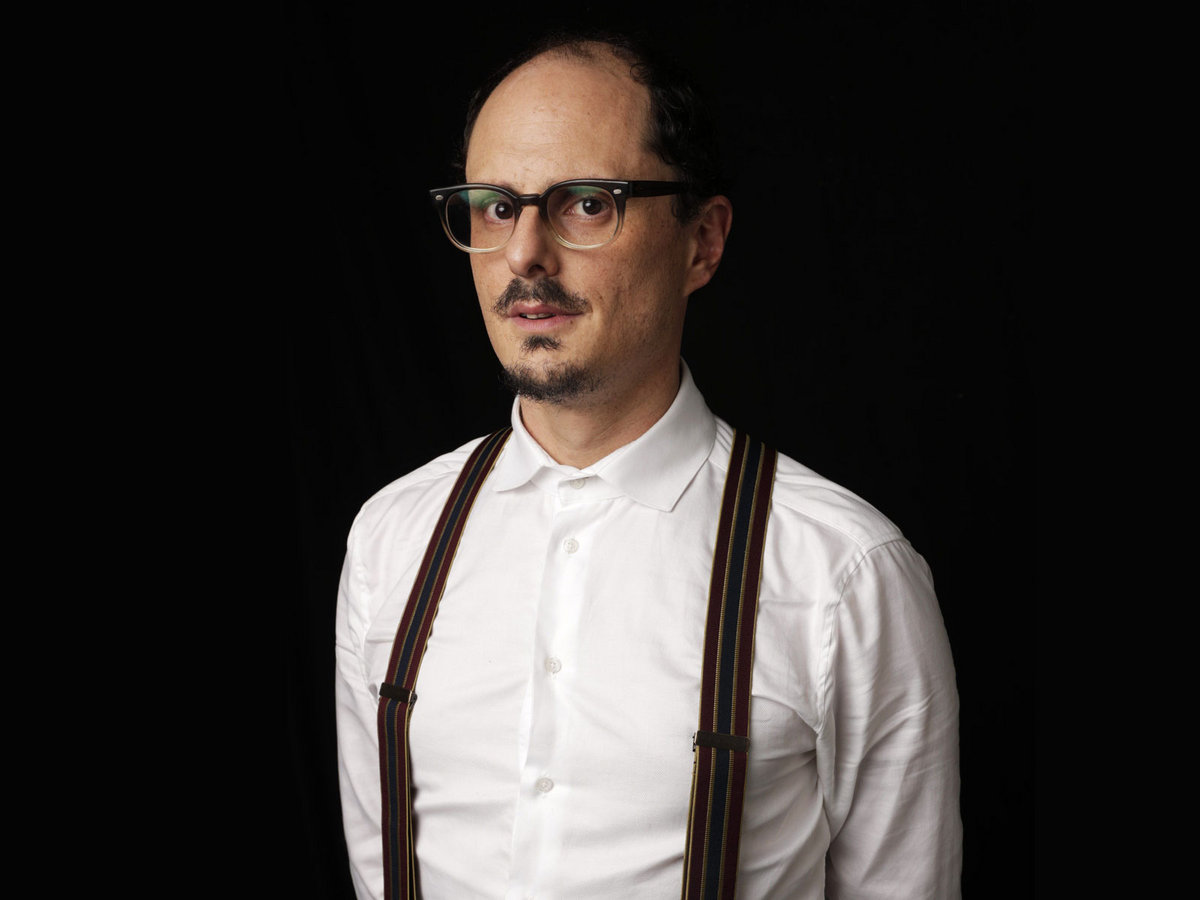 Socalled, aka Joshua Dolgin, in a white button-down shirt, suspenders, and glasses