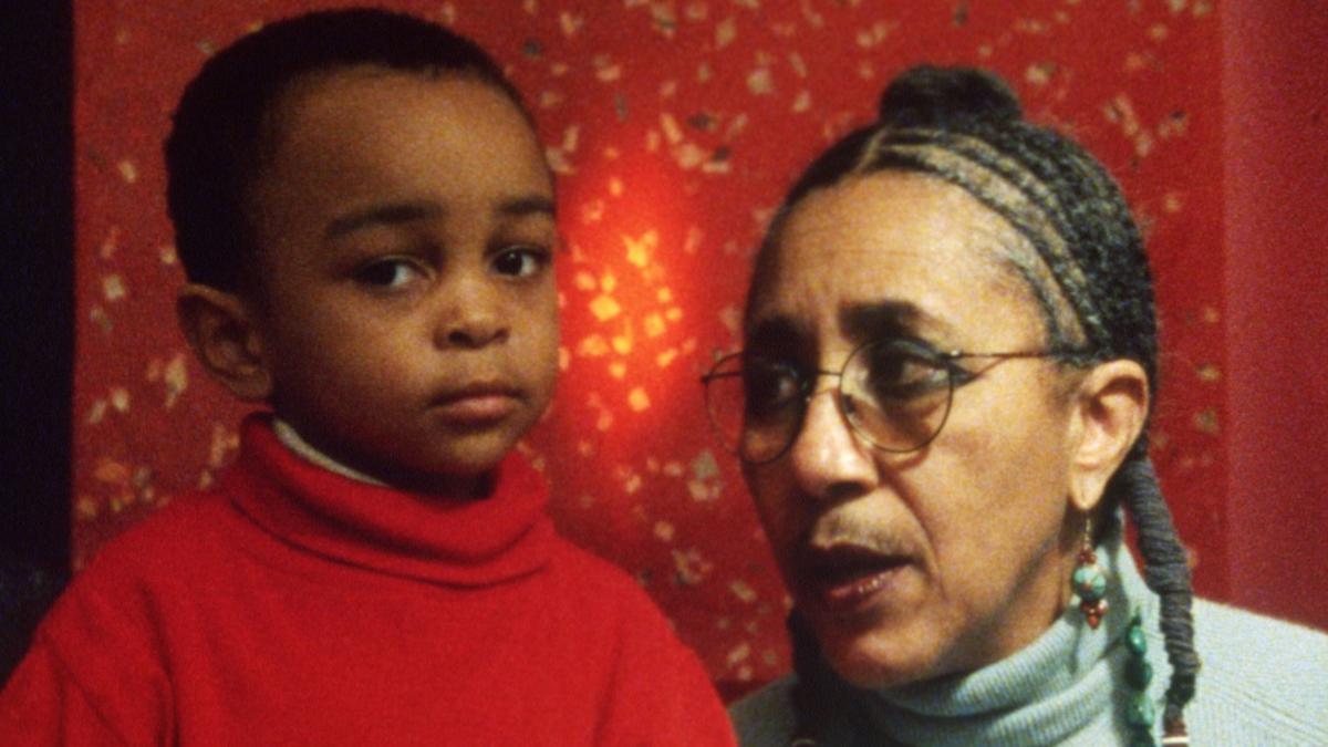 the faces of a Black baby and old woman against a red background